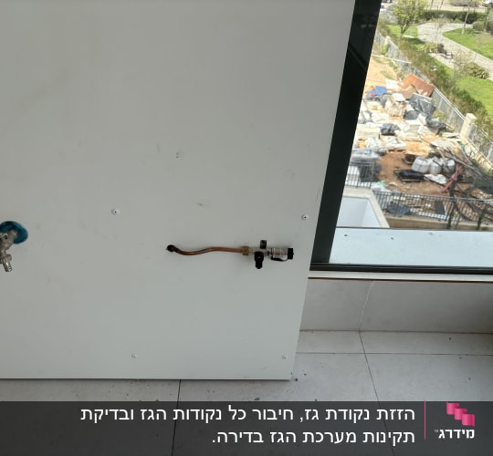 ברז מתכת עם ידית אדומה על קיר לבן
